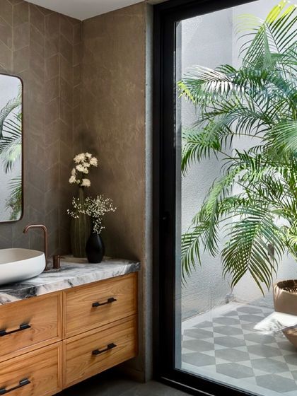 This bathroom in the Mango Orchard House opens up to a private, open-to-sky courtyard, bringing light and nature directly into the space. The earthy tones of the tiles and the wooden vanity connect the interior to the outdoors.