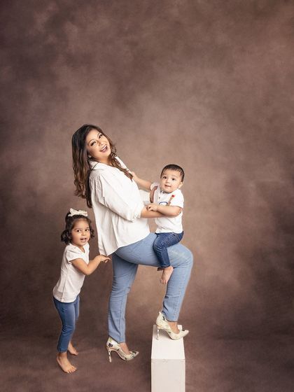 A fun, dynamic pose showing a mother's strength and her children's playful nature. This image is full of energy and joy.