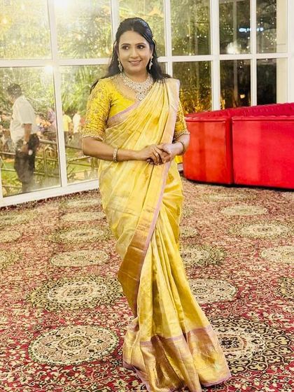 Babitha at an event, her golden saree shimmering and making her stand out.