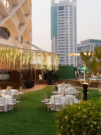 The reception setup at Jade Banquets, showing the contrast between the lush green lawn and the sparkling floral canopy.