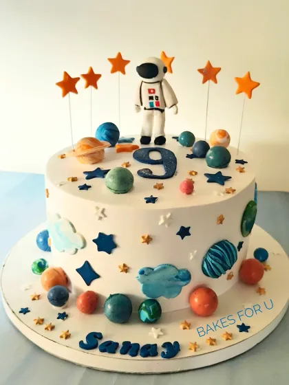 A solar system cake perfect for a budding astronaut. This design is decorated with edible planets, stars, and an astronaut figure, making learning about space delicious and fun.