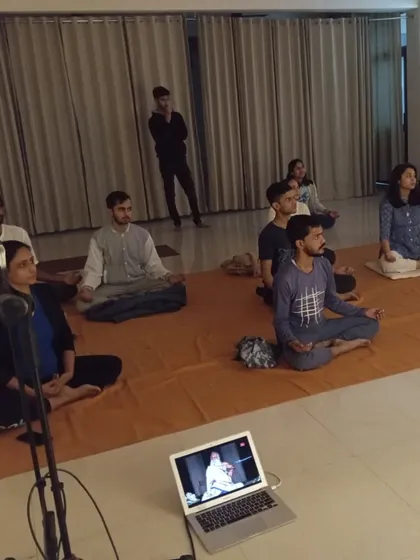 Participants sit in stillness during a guided meditation with Sadhguru on screen. The consecrated space amplifies the experience, making it deeply transformative.