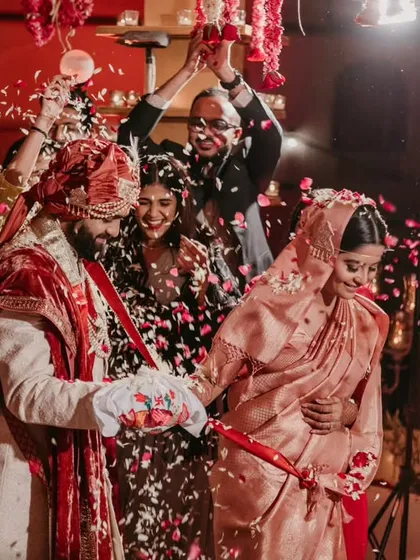 A candid moment during the pheras, with family members joyfully showering the couple with petals.