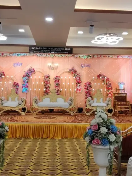 A traditional stage setup for a Maharashtrian wedding at Devadiga banquet hall. The decor features multiple golden chairs for family rituals and a colorful floral backdrop, keeping the focus on the ceremony.