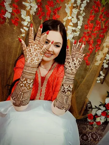 The perfect bridal pose. A smiling bride showing off her detailed back-hand mehandi design.