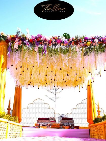 An open-air mandap at Ikshana Resort, featuring a canopy of hanging flowers against a clear blue sky. This design brings a touch of magic and grandeur to an outdoor wedding.