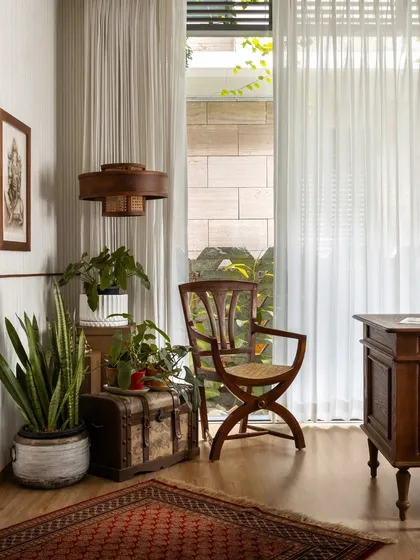 This cozy corner in the study is filled with layered textures, from the antique trunk to the patterned rug, and lots of greenery.