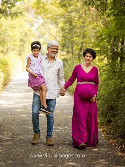 A candid moment during an outdoor family maternity session. The father carries his daughter while holding hands with his expectant wife, capturing the love and movement of this growing family.