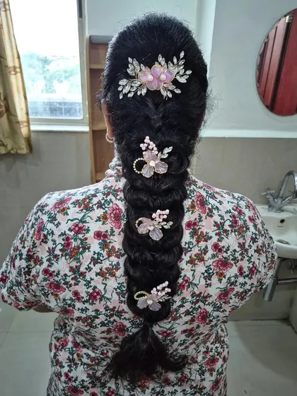 A lovely messy braid decorated with delicate pink and white floral pins. This is a great option for a softer, more romantic traditional look.