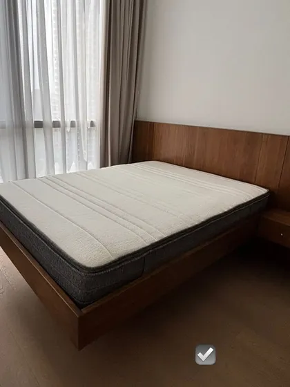A minimalist floating bed design with an extended headboard that incorporates a built-in side table. This custom piece is perfect for creating a clean, uncluttered look in a modern bedroom.