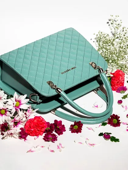 The same mint green bag, shot from a top-down angle and surrounded by flowers. This flat lay style gives a different perspective and feels fresh and spring-like.