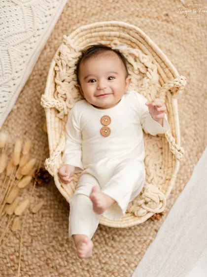 A happy baby lying in a basket during a 6-month milestone session. The simple, neutral setup keeps all the focus on that infectious smile.
