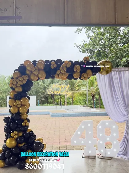 A sophisticated black and gold theme for a 48th birthday. This outdoor setup features a balloon arch and large marquee numbers.
