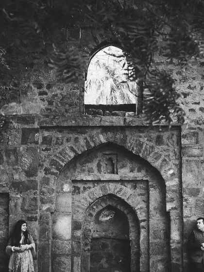 A dramatic, wide-angle shot at a historic ruin in Delhi. The ancient stone and shadows create a powerful and artistic pre-wedding portrait.