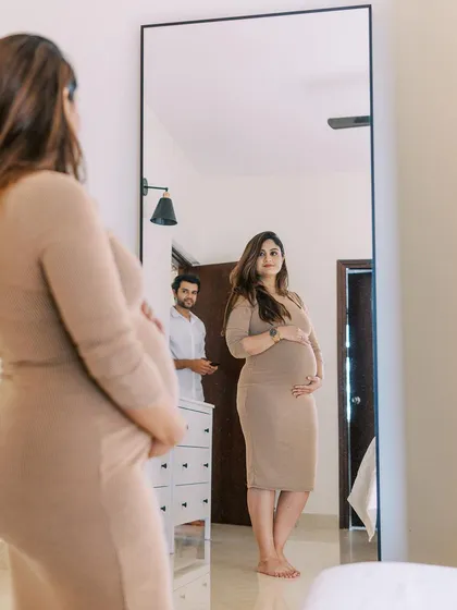A full-length mirror provides a wonderful opportunity for a reflective portrait. Here, the mother-to-be sees herself in this new way, with her partner looking on, a quiet moment of acknowledgment and anticipation.