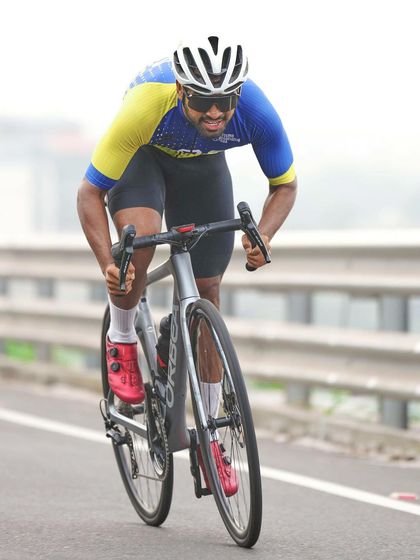 A tighter shot of a cyclist pushing the pace. The low angle emphasizes his power and speed, while the focused expression shows the immense effort involved in competitive road cycling.