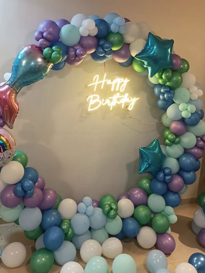 Dive into an under-the-sea adventure with this mermaid theme. A beautiful balloon ring in shades of purple, green, and blue, complete with a mermaid tail foil balloon and a neon sign, creates a magical photo corner.