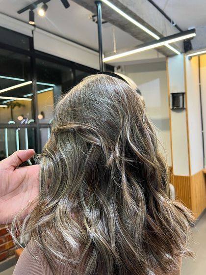 The hand of the stylist showing the texture and color of the finished ash blonde look.