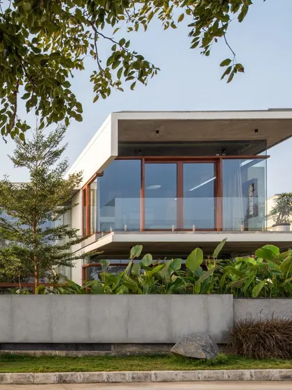A detail of the cantilevered first-floor balcony, which is wrapped in glass to provide uninterrupted views. The lush greenery in the foreground is part of our integrated landscape design.