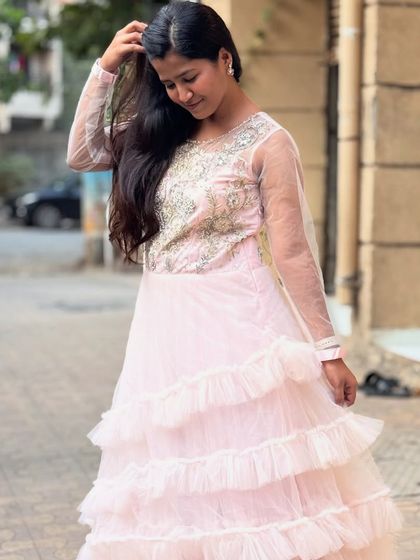 This baby pink tiered gown with an embroidered bodice is a soft and romantic choice for any party. The ruffles add a playful touch.