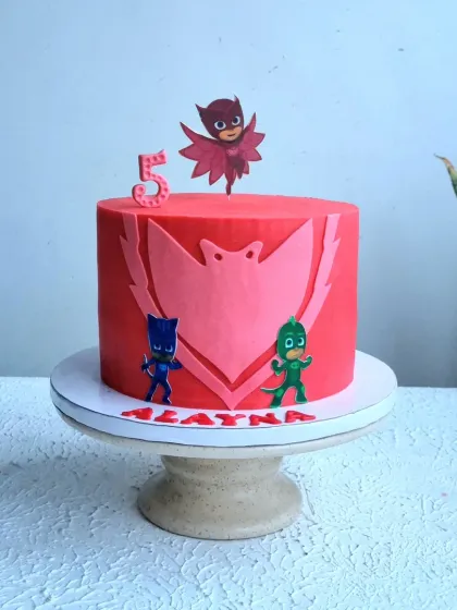 A full view of the red PJ Masks cake on its stand.