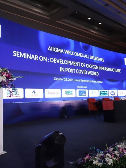 A professional setup for a corporate seminar on post-covid infrastructure. The stage features a large, branded LED screen and a panel seating area, designed for clarity and impact.