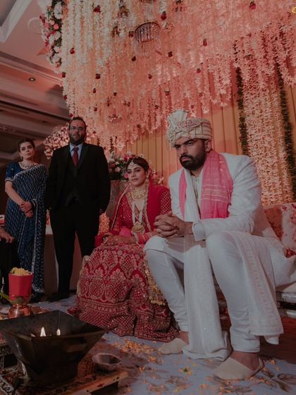 The couple seated at the mandap, listening to the priest during their Pheras.