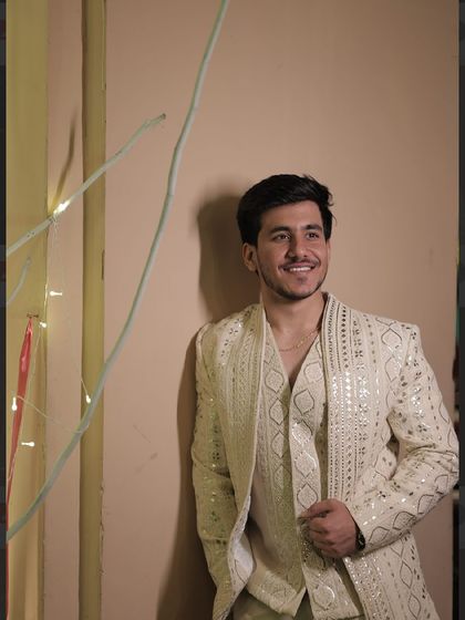 A candid moment with our client in his designer jacket set. The intricate mirror work catches the light beautifully, making it perfect for an evening Sangeet or reception.