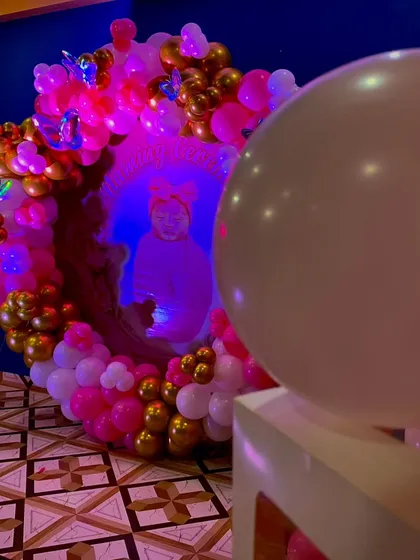 An artistic shot of the Naming Ceremony backdrop, with a large white balloon in the foreground, highlighting the beautiful pink and gold balloon ring.