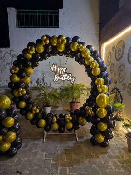 This wide shot shows the full scale of the circular balloon arch against the wall of a building, ideal for restaurant patios or terraces.