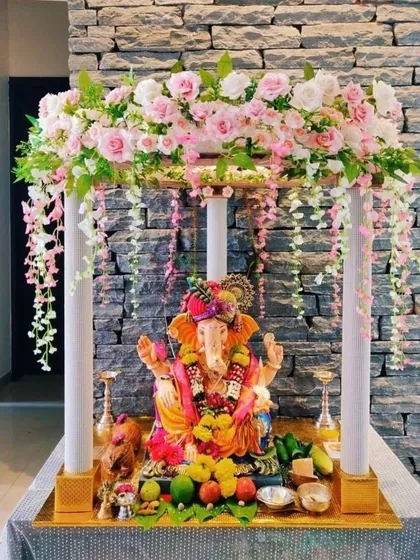 This elegant four-poster mandap is adorned with pink and white flowers and hanging floral strings. It's a simple yet sophisticated design, perfect for modern homes.