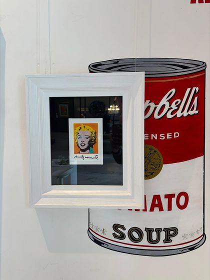 Another view of the framed Marilyn Monroe postcard by Andy Warhol. His work explores the relationship between artistic expression, advertising, and celebrity culture.