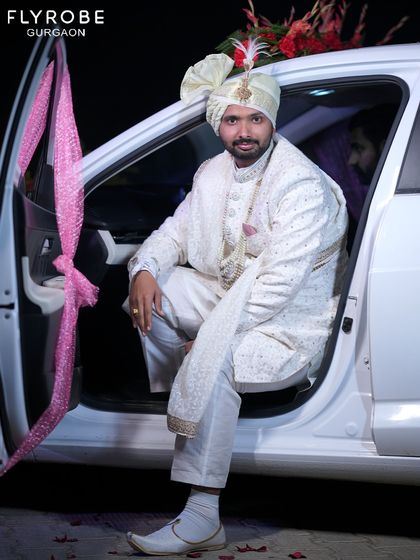 Arrive in style. This groom is wearing a classic white embroidered sherwani, complete with a safa (turban) and mala (necklace), which are also available for rent to complete your look.