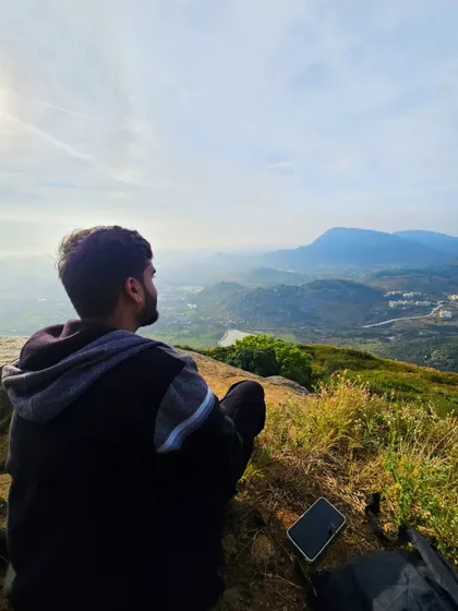 Finding peace and solitude at the summit. A trekker sits and enjoys the panoramic view of the mountains and valleys from Skandagiri.