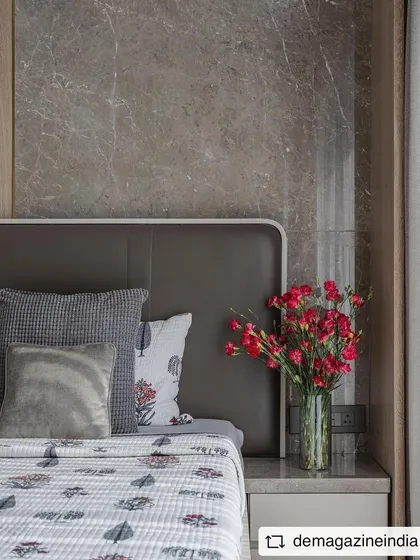 A detail shot from the 'Aria Residence' bedroom, showing the combination of a grey marble headboard panel with warm wood and a leather-upholstered bed frame.