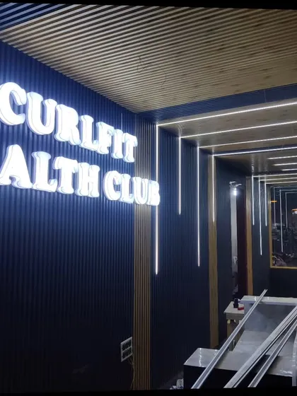I also specialize in commercial interiors, like this project for Curlfit Health Club. I used a combination of dark WPC louvers for the walls and lighter wooden-finish panels for the ceiling to create a modern and energetic vibe. The backlit 3D signage adds a professional finishing touch.