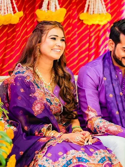 The bride and groom sharing a moment, her hair styled in soft waves that complement her traditional yet festive attire.