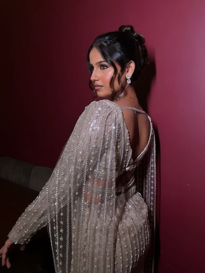 A look at the back details of the outfit and hairstyle. The makeup remains flawless from every angle, featuring a sultry smokey eye and radiant skin.
