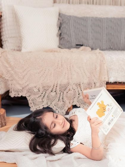 In my little dreamland. This older child is enjoying a quiet moment reading a book in our cozy, bohemian studio setup. Milestone sessions are for kids of all ages.