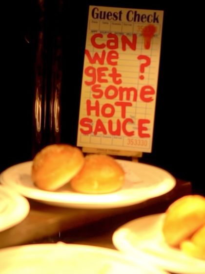 A playful detail from our burger station. A sign styled like a guest check asks, "Can we get some hot sauce?" adding a touch of personality and fun to the setup.