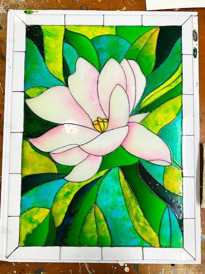 A beautiful stained glass painting of a magnolia flower, created by a student in one of our customized workshops.