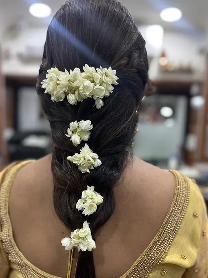 A classic South Indian bridal hairstyle. This traditional thick braid is beautifully adorned with fresh jasmine flowers, or gajra, creating a timeless and fragrant look for the wedding day.