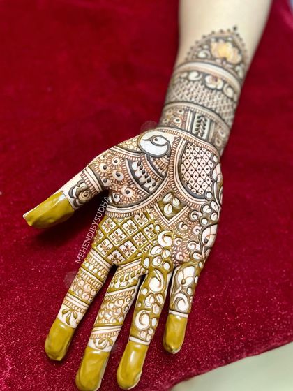 A single hand from an engagement design, featuring a graceful peacock and intricate check and floral patterns.