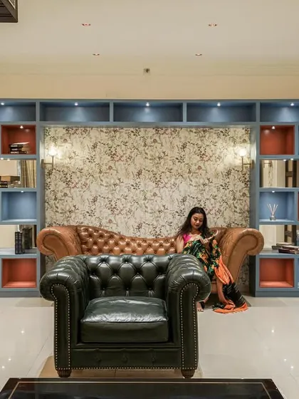 A luxurious living room with classic Chesterfield sofas and a custom blue bookshelf unit, showcasing a blend of modern and traditional styles.