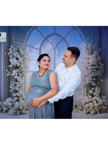 An intimate studio portrait of the couple embracing, both looking at each other with love as they hold the baby bump.