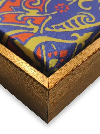 A vibrant scarf, full of detail and charm, becomes a stunning piece of wall art. We stretched and mounted the fabric in a floater frame to showcase its texture and design as a unique decorative item.
