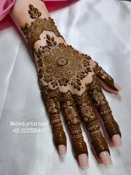 Another view of the mandala design on a practice hand. This angle highlights the detailed work on the fingers, where each segment has a unique pattern that complements the main design.