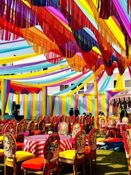A unique and playful Mehendi setup, featuring custom pop-art chairs and brightly colored drapes, showing how we can tailor the decor to a fun, modern theme.