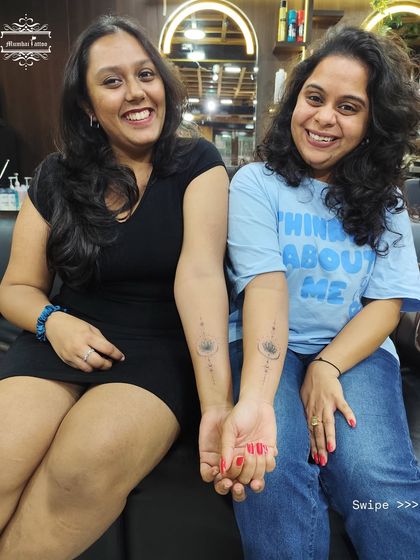 Two friends showing off their matching Unalome lotus tattoos. This spiritual symbol represents the journey to enlightenment, a beautiful path to walk together.