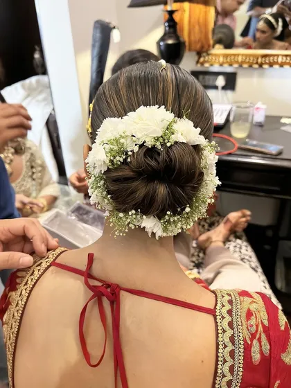 A classic Sabyasachi bride look with a clean, traditional bun adorned with a halo of fresh white flowers.